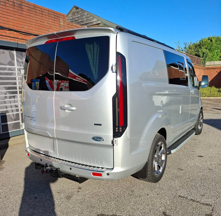 Rear three-quarter view of a silver Ford Transit Custom with smoked LED rear light units